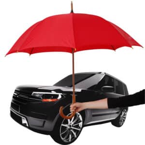 A person holds a large red umbrella in front of a black SUV, shielding part of the vehicle’s front, as if pondering: Does Car Insurance Cover Hail Damage? The background is plain white.